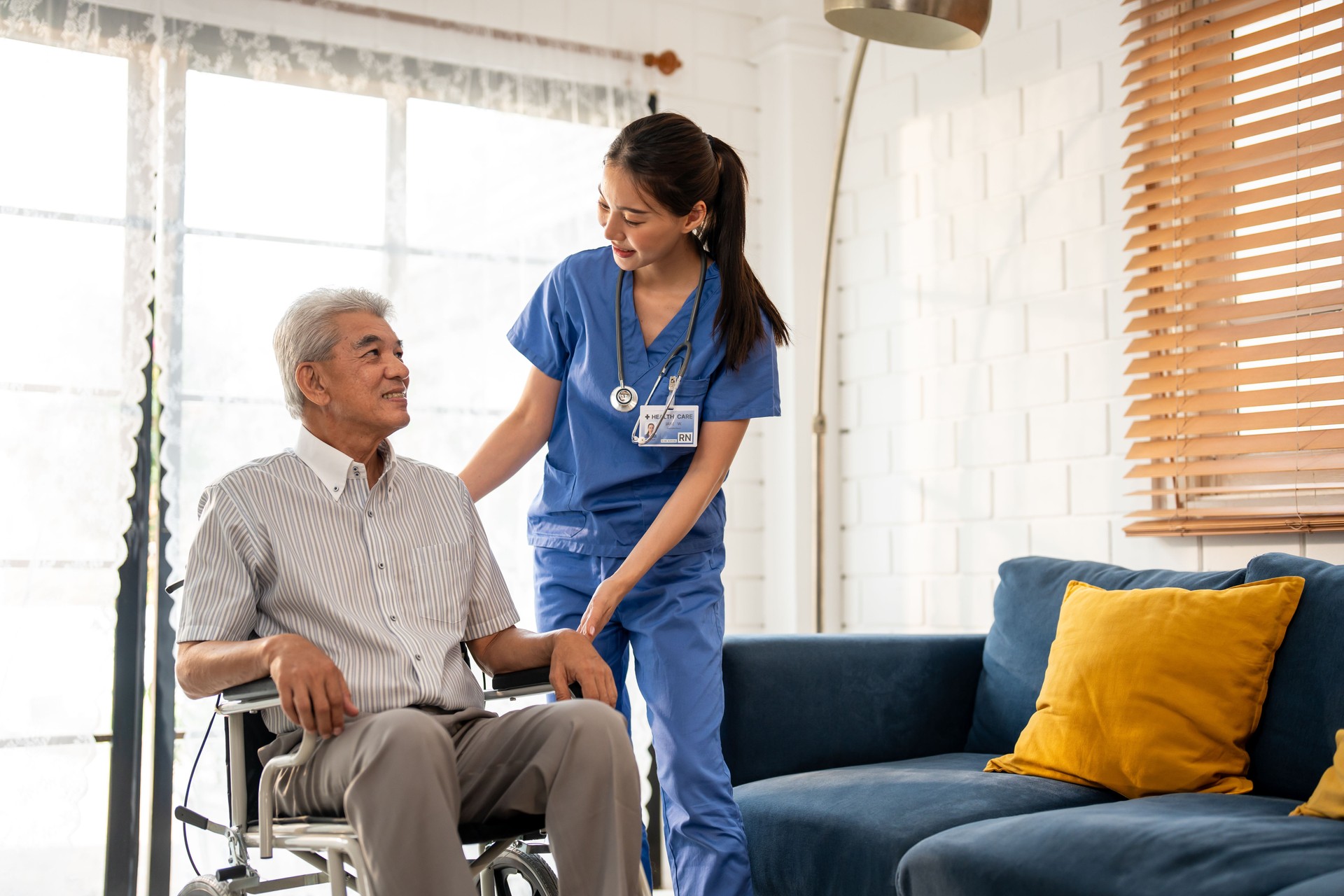 home health aide assisting elderly man with mobility and supportive care in North Port Florida living room