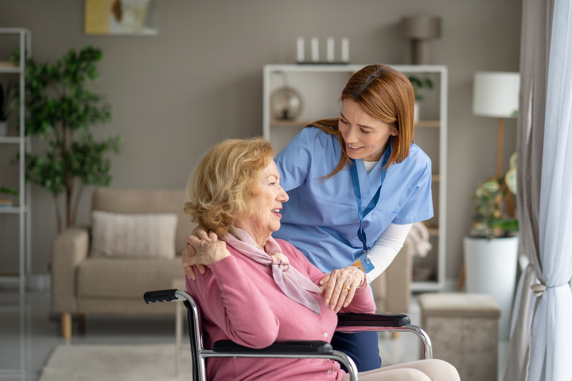 Compassionate nurse with arm around elderly woman in wheelchair providing personal care and emotional support at home in Port Charlotte, FL.
