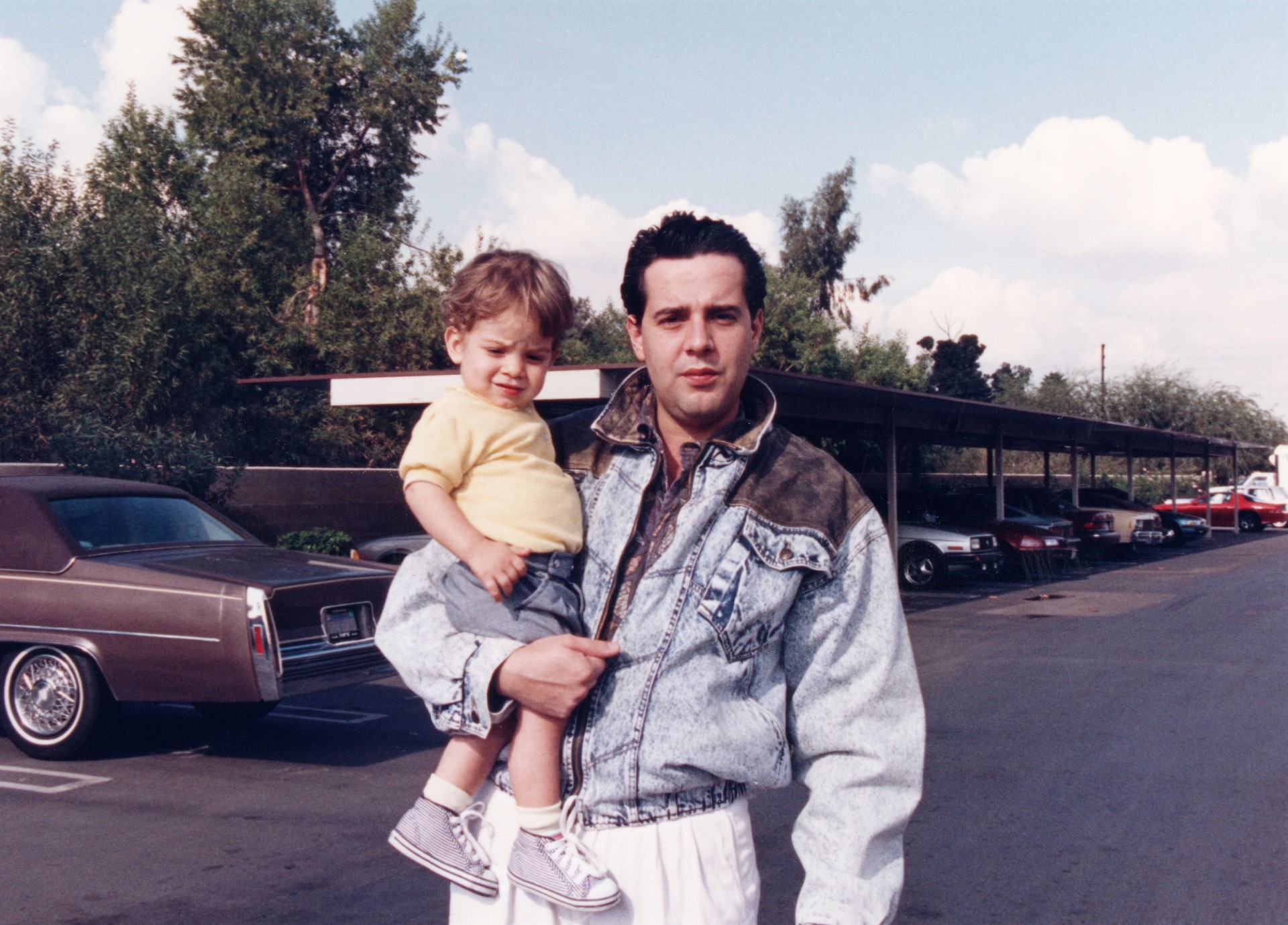 photo taken in 1988 in California, young man posing holding his son looking at the camera